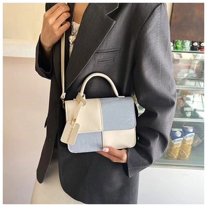 Detail view of contrast color stitching and leather texture on a mini square handbag