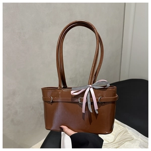 Detail of brown patent leather handbag with glossy finish and pink checkered bow accent