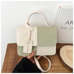 Detail of cream and green leather stitching on a mini square fashion handbag with handle
