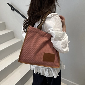 Pink corduroy tote bag with brown trim and large capacity for women on a shoulder view