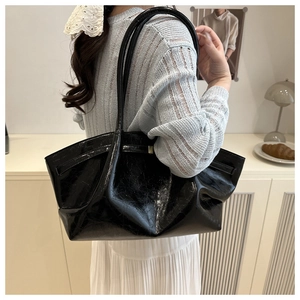 Close-up of black oil wax leather tote bag with elegant pleated texture and slim handles