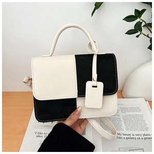Detailed view of black and white contrast PU leather handbag with elegant top handle