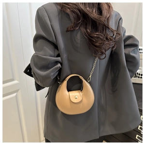 Detailansicht einer khakifarbenen Halbmond-Tasche mit goldener Kette auf einem Modell