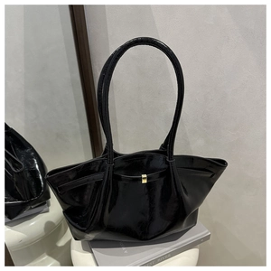 Close-up of glossy black leather tote bag with elegant golden buckle and ruched detail