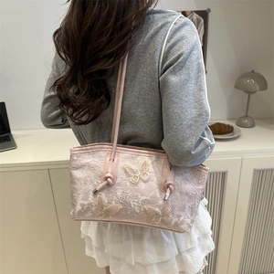 Pink lace underarm bag with 3D butterfly embroidery shown on a model in a cozy room