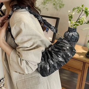 Elegant black sequined embroidery bucket bag with ruffled strap shown on model shoulder