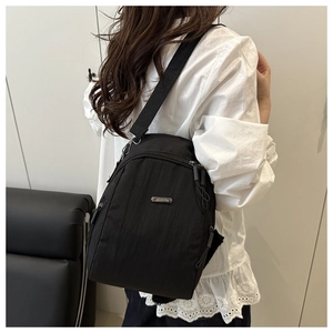 Detail of water-resistant black nylon backpack showing zippers and metal logo