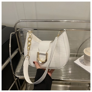 Close-up of white crocodile pattern bag with gold chain and metal D-buckle detail