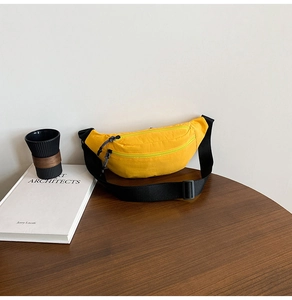 Detail of yellow nylon crossbody bag with dual zippers and black adjustable strap