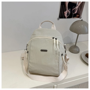 Detailed macro view of the light beige nylon backpack with brand plaque and zippers