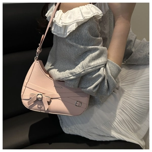 Model wearing a pink half-moon shoulder bag with bow buckle detail and adjustable strap