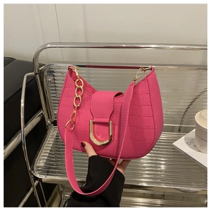 Detail of fuchsia crocodile embossed crescent bag with gold buckle on a stylish chair
