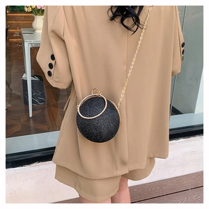 Detail of a black sequined sphere evening bag with a gold chain and crystal ring handle