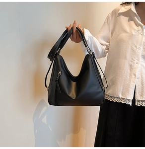 Detail shot of black glossy PU leather shoulder bag with decorative diagonal zipper design