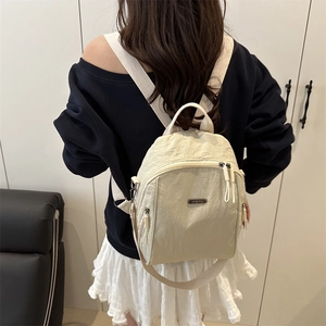 Minimalist beige lightweight large capacity backpack shown on a model from the back view
