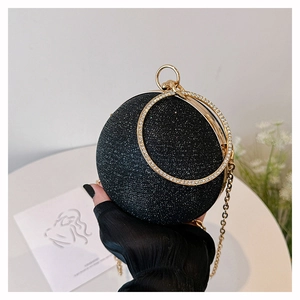 Detail of a spherical black glitter evening bag with diamond gold ring handles and chain