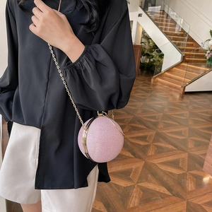Sparkly pink spherical evening bag with gold chain strap shown on a model's outfit