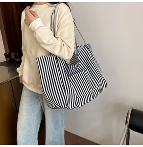 Detail of a large black and white striped canvas tote bag with functional front pocket