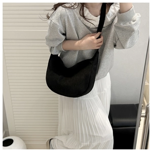 Black corduroy hobo bag on model with textured rib detail and casual crescent shape