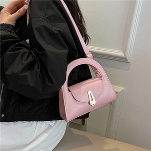 Pink minimalist handbag with unique wide handle and golden shield buckle on model
