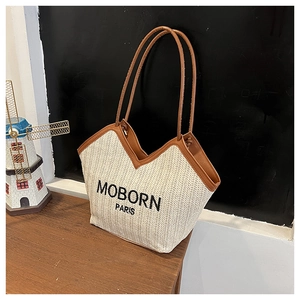 Détail du cabas en paille tissée avec bordure en cuir marron et broderie MOBORN PARIS