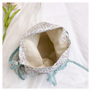 Detail view of floral drawstring bucket bag showing spacious interior lining and checkered strap