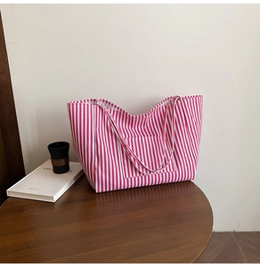 Close-up of red and white striped canvas tote bag with front pocket on wooden table