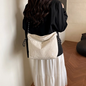 Minimalist beige waterproof nylon crossbody bag with black and white woven strap