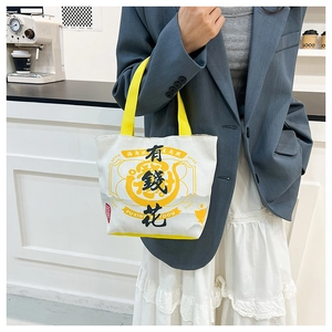 Detail of canvas tote bag with Chinese calligraphy and yellow handles in cafe setting