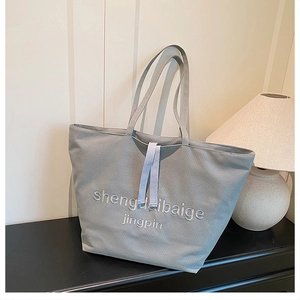 Detail of grey canvas tote bag with embroidered logo on premium fabric texture