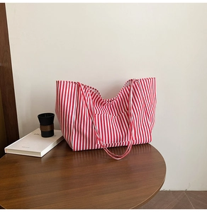 Detailed macro view of red and white striped canvas tote bag with front pocket design