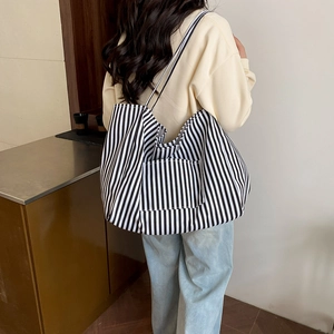 Black and white striped canvas tote bag with front pocket shown on a model for daily style