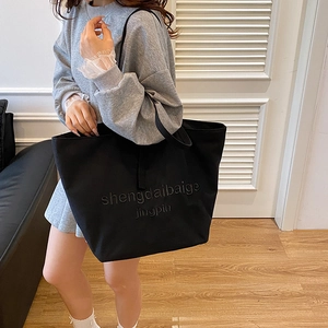 Minimalist black large canvas tote bag with embossed text for casual shoulder wear