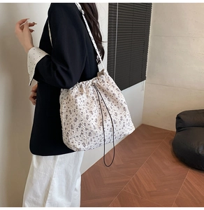 Detail of drawstring floral canvas bucket bag with purple patterns and shoulder strap
