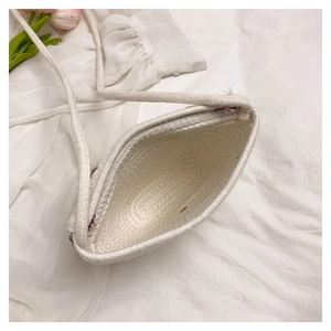 Top view of white woven straw bag with purple floral details and rope shoulder strap