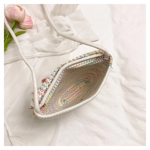 Detail of hand-woven straw bag with colorful zigzag stitching and thin shoulder strap