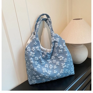 Dettaglio del ricamo floreale 3D sulla borsa tote azzurra in tela da donna