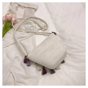 Detail of white woven bucket bag featuring colorful tassels and thick cotton rope strap