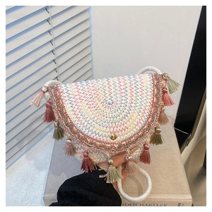 Detail shot of bohemian woven straw bag with colorful zigzag patterns and tassel trim
