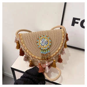 Detail of bohemian straw bag featuring colorful beadwork and tiered decorative tassels