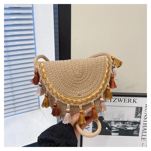 Detailed view of handmade woven straw bag with colorful tassels and golden embroidery