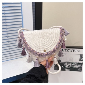 Close-up of bohemian woven straw bag with purple fringe tassels and metal snap button