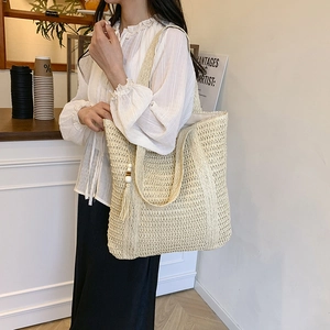 Large beige woven straw tote bag with long tassel and wooden beads for summer vacations