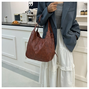 Close-up of caramel faux leather tote bag with embossed square detail and wide straps