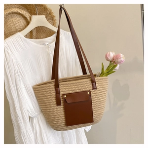Detail of summer straw tote bag with brown leather handles and a front pocket