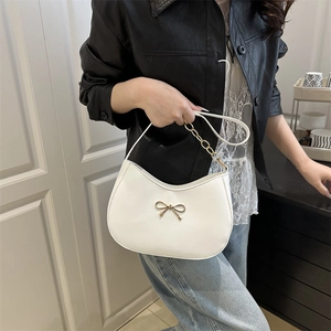 White crescent hobo bag with a gold metal bow and elegant chain shoulder strap