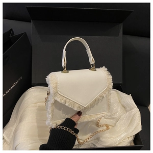 Vue détaillée du mini sac en cuir blanc avec pompons et chaîne dorée en coffret cadeau