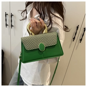 Detail of trendy green square bag featuring a gold ring handle and woven texture flap