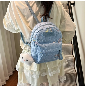 Detail of light blue quilted backpack with bow embroidery and star plush pendant charm