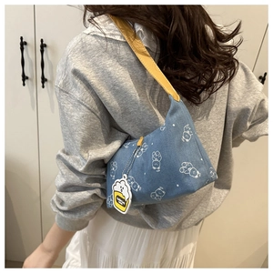Detail of blue denim shoulder bag with white bear prints and yellow leather strap